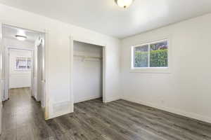 Unfurnished bedroom featuring dark hardwood / wood-style floors and a closet