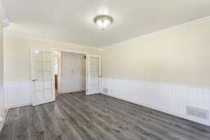 Empty room featuring ornamental molding, french doors, and dark wood-type flooring