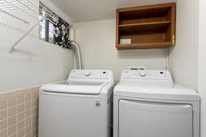 Washroom featuring separate washer and dryer and tile walls