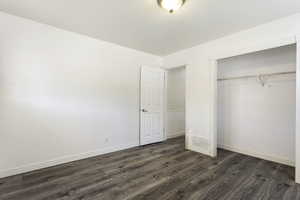 Unfurnished bedroom with a closet and dark wood-type flooring