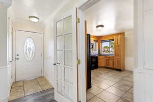 Foyer entrance featuring ornamental molding and light tile floors