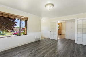 Spare room featuring dark hardwood / wood-style floors and crown molding