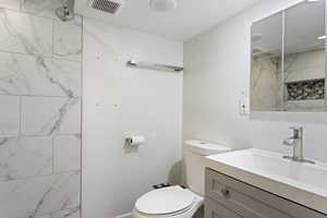 Bathroom featuring vanity with extensive cabinet space and toilet