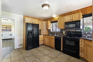 Kitchen featuring sink, light tile flooring, tasteful backsplash, and black appliances