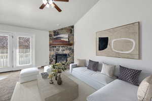 Living room with light carpet, lofted ceiling, ceiling fan, and a stone fireplace