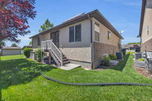 Rear view of property featuring a yard and central air condition unit