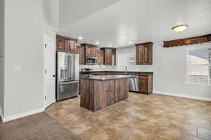 Kitchen with a textured ceiling, a kitchen island, sink, and appliances with stainless steel finishes