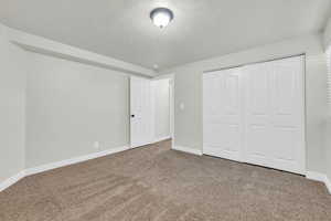 Unfurnished bedroom with a textured ceiling, carpet, and a closet