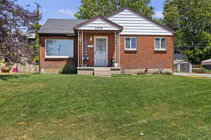 Bungalow-style home with a front yard and a storage unit