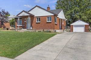 Bungalow with a front yard, a garage, and an outdoor structure