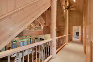 Hallway with beamed ceiling, high vaulted ceiling, wooden ceiling, and light colored carpet