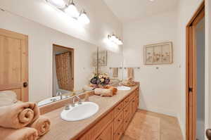 Bathroom featuring tile floors, dual sinks, and vanity with extensive cabinet space