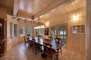 Dining room featuring tile flooring, plenty of natural light, beam ceiling, and wooden walls