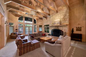 Living room featuring a fireplace, beamed ceiling, wooden ceiling, wooden walls, and carpet flooring