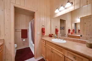 Full bathroom with wood walls, oversized vanity, and toilet