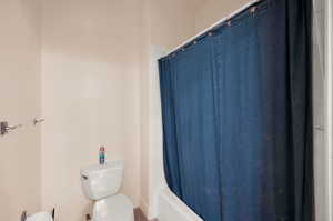 Bathroom with shower / bathtub combination with curtain and toilet