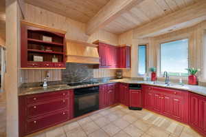 Kitchen with light stone countertops, beam ceiling, custom exhaust hood, and black appliances