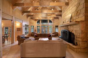 Tiled living room with a stone fireplace, wooden ceiling, plenty of natural light, and beamed ceiling