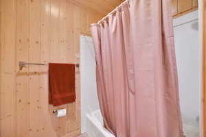 Bathroom with shower / tub combo and wood walls