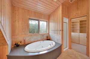 Bathroom featuring vaulted ceiling, wooden walls, wooden ceiling, and plus walk in shower