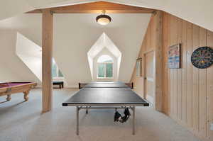 Game room with billiards, vaulted ceiling, carpet floors, and wood walls