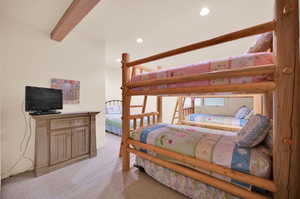 Bedroom featuring light colored carpet and beam ceiling