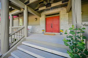 Doorway to property featuring ceiling fan and a porch