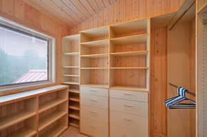 Walk in closet featuring vaulted ceiling and light carpet