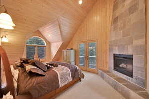 Bedroom featuring a fireplace, access to outside, wooden walls, lofted ceiling, and wooden ceiling