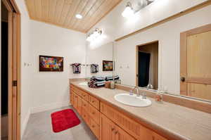 Bathroom with wood ceiling, tile floors, large vanity, and double sink