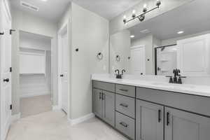 Bathroom featuring dual vanity, a textured ceiling, tile patterned flooring, and an enclosed shower