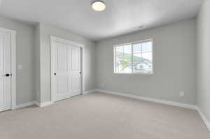 Unfurnished bedroom with light carpet and a textured ceiling