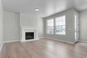 Unfurnished living room featuring light wood-type flooring and a textured ceiling