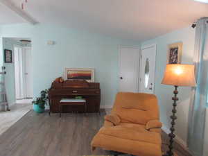 Living area with vaulted ceiling with beams and hardwood / wood-style floors