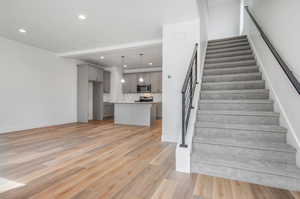 Stairway featuring sink and light hardwood / wood-style floors