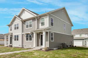 View of front of home with a front yard, a garage, and central air condition unit