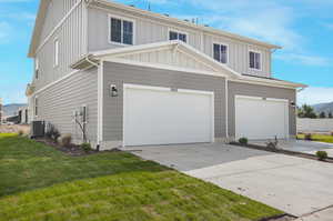 View of front of property with a garage, a front yard, and central air condition unit