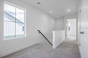 Corridor with a healthy amount of sunlight and light colored carpet