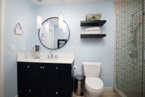 Bathroom with tile floors, walk in shower, toilet, and vanity