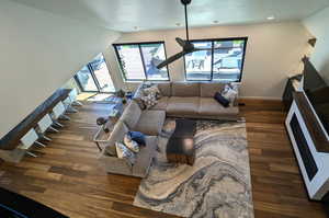 Living room with ceiling fan, dark hardwood / wood-style floors, and lofted ceiling