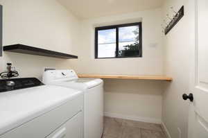 Washroom with light tile flooring, washer hookup, and washing machine and clothes dryer