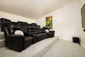 Carpeted cinema room featuring lofted ceiling