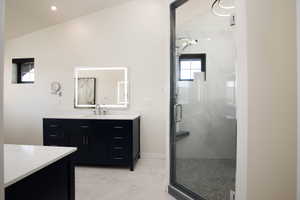 Bathroom featuring a shower with shower door, tile flooring, lofted ceiling, and vanity