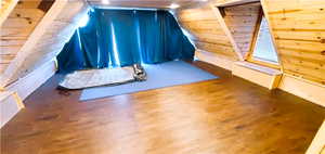 Bonus room with wood walls and wood-type flooring