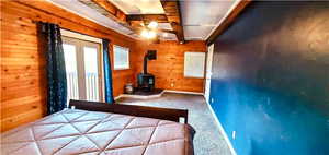 Unfurnished bedroom featuring carpet floors, wood walls, and a wood stove