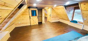 Basement featuring wood walls, a barn door, and dark hardwood / wood-style floors