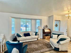 Living room featuring a textured ceiling, an inviting chandelier, and hardwood / wood-style floors