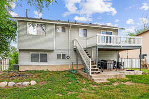 Back of property with a patio, a wooden deck, and a yard