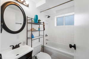 Full bathroom featuring tiled shower / bath, vanity, and toilet