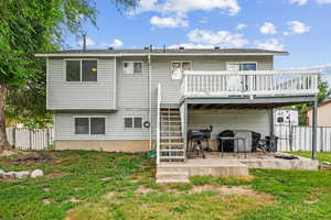 Rear view of house featuring a patio area, a deck, and a lawn